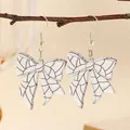 Detail of white bow earrings with black grid pattern hanging on a natural branch - Black and White Grid Style