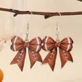 Detail of American football bow earrings featuring textured acrylic and silver hooks - Brown Football Style