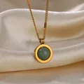 Macro shot of gold oval pendant with green stone on ivory silk background fabric - Round Green Stone Style (G6206975)