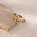 Detail of minimalist 18K gold plated stainless steel ring on beige travertine stone - Gold Wavy Abstract Line Style (G8316975) / Gold