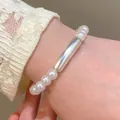 Detailed close-up of a minimalist pearl bracelet with a silver tube on a lace sleeve - Silver Tube Artificial Pearl Style / Bright Silver (6930)