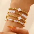 Set di quattro bracciali bohémien con perline, ciondoli a croce bianchi e sfere dorate - Stile Croce Bianca (A-813)