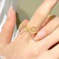 Minimalist gold bow-shaped hollow ring for women shown as worn on index finger - Gold Bow Ring (N-684)