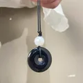 Dettaglio ciondolo Ping An Kou in ossidiana nera con perla bianca su collana intrecciata - Nero Lucido (N-122)