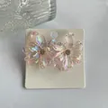 Y2K iridescent flower earrings with crystal center on white display card - Light Pink