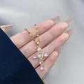 Detailed macro of gold cross pendant with pink zircons held against a silk background - Light Pink