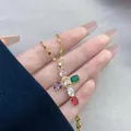 Detailed view of a gold cross pendant featuring vibrant multi-colored oval gemstones - Mixed Colors
