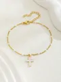 Dettaglio di bracciale a croce dorata con perline in smalto bianco e chiusura a moschettone - Stile Pendente Verticale