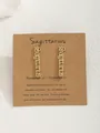 Gros plan de boucles d'oreilles Sagittaire dorées sur carte kraft avec détails zodiac - Sagittaire-Or