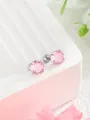 Dettaglio di orecchini con zirconi rosa e chiusura a vite argentata su supporto elegante - Zircone Rotondo