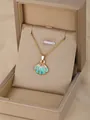 Golden necklace with a green and pink enamel scallop shell pendant in a jewelry box - Scallop-Blue