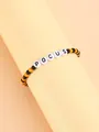 Detalle de pulsera de cuentas naranjas y negras con dijes de letras que dicen POCUS - Naranja Negro Blanco Letra POCUS