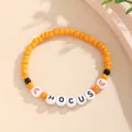 Detalle de la pulsera de cuentas naranjas con letras HOCUS y motivos de lunas negras - Naranja Negro Blanco HOCUS Luna
