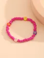 Detalle de una pulsera de cuentas coloridas con estrellas y flores sobre fondo arena - Rosa Rojo Estrella Estilo Floral
