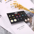 Detailaufnahme eines 9-teiligen Ohrring-Sets mit Gänseblümchen und Sternen auf Karte - Exquisite Blume Stern Strasskugel