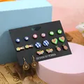 Nahaufnahme eines 9-Paar-Sets mit bunten Herz-, Marienkäfer- und Blumenohrsteckern - Schmetterling Herz Karo Legierung