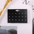 Detailansicht von 9 Paar sortierten weißen Strass-Ohrsteckern auf schwarzer Displaykarte - Strass Metall Mode
