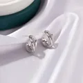 Silver twisted C-shape hoop earrings with sparkling cubic zirconia on purple silk background - Crossed Double Line Silver-Tone Earrings