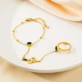 Exquisite gold snake ring bracelet set with green gemstones on elegant silk fabric - Green Stone Snake Style
