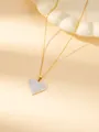 Dettaglio di una collana con ciondolo a cuore dorato e cristalli su sfondo beige - Collana cuore pavé zircone bianco