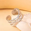 Makroaufnahme eines gewebten Edelstahlrings in Silber auf einem Stein-Podest - Mehrschichtig Dünnes Band Kreuz Hohl Stil (BJGR0349) / Silber