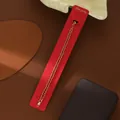 Dettaglio del bracciale a doppia catena placcato oro con fibbia di strass su carta rossa - Oro