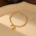 Primer plano detallado de pulsera con cuentas doradas y colgante de caballo - Dorado