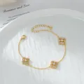 Bracciale a quadrifoglio dorato con zirconi su un piatto bianco effetto acqua - Oro