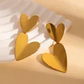 Polished gold double heart stainless steel drop earrings on a white display stand - Gold Heart Earrings (BJGE1187)
