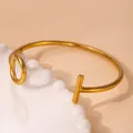 Minimalist gold sunflower open cuff bracelet featuring a toggle clasp on a white plate - T-bar Hook Geometric Style