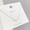Detailed close-up of a golden elk antler pendant necklace on a white display card - Gold