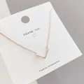 Close-up of rose gold elk antler pendant necklace on white display card with chain details - Rose Gold