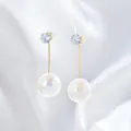 Dettaglio macro di lunghi orecchini placcati in oro con zirconi lucenti e grandi perle tonde - Stile Perla Zirconia Oro