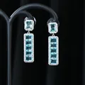 Dettaglio di orecchini pendenti in argento con pietre blu rettangolari e pavé di cristalli - Argento Smeraldo