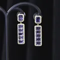 Dettaglio ravvicinato di orecchini pendenti vintage in oro con cristalli viola rettangolari - Oro Viola
