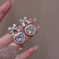 Dettaglio degli orecchini a cuore in argento con fiocchi e micro-pave di zirconi - Argento
