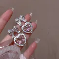 Dettaglio dell'orecchino a cuore rosa con fiocco a farfalla e micro-set di zirconi - Rosa