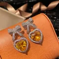 Dettaglio di orecchini a fiocco in argento con cuore giallo su scatola di gioielli - Giallo