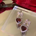 Dettaglio di orecchini a cuore rosso con fiocco di diamanti in stile festivo - Rosso