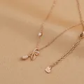 Detailed macro view of gold-plated necklace with bow pendant and pink drop stone - Bowknot Cat Eye Stone Style (XL62396) / Rose Gold