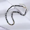 Dettaglio collana con perline cilindriche marmorizzate, distanziali dorati e chiusura - Stile Marmo Nero Bianco Grigio(XL896049)