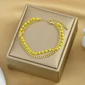 Dettaglio di un bracciale a doppio strato dorato con perline gialle su raso - Giallo Dorato