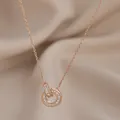 Collana in oro rosa con doppi anelli intrecciati e zirconi su sfondo di seta beige - Oro rosa