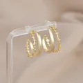 Macro view of gold geometric C-shaped earrings with dual-layer wavy zircon pavé design - Gold