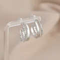Detail of silver C-shaped double hoop earrings with cubic zirconia and milgrain edges - Silver