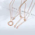 Collana a strati in oro rosa con ciondolo a triplo anello e zircone su sfondo bianco - Stile Doppio Strato Triplo Anello Zirconia (XL61685) / Oro rosa