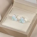 Dettaglio di orecchini con pietre preziose blu quadrate in una scatola di seta dorata - Blu Argento
