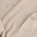 Detailopname van zilveren maan- en sterhanger ketting op beige getextureerde stof - Zilver