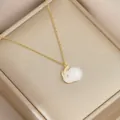 Detailed view of a gold-plated rabbit pendant with faux jade inlay on champagne silk - Gold