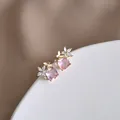Dettaglio ravvicinato di orecchini con gemma rosa e farfalla dorata con motivi floreali - Oro (Rosa)